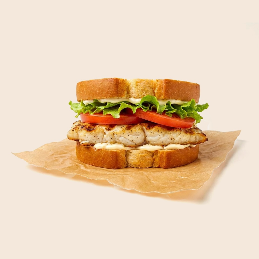 Grilled walleye fish sandwich on toasted bread with lettuce, tomato, and mayo-based tartar sauce. 