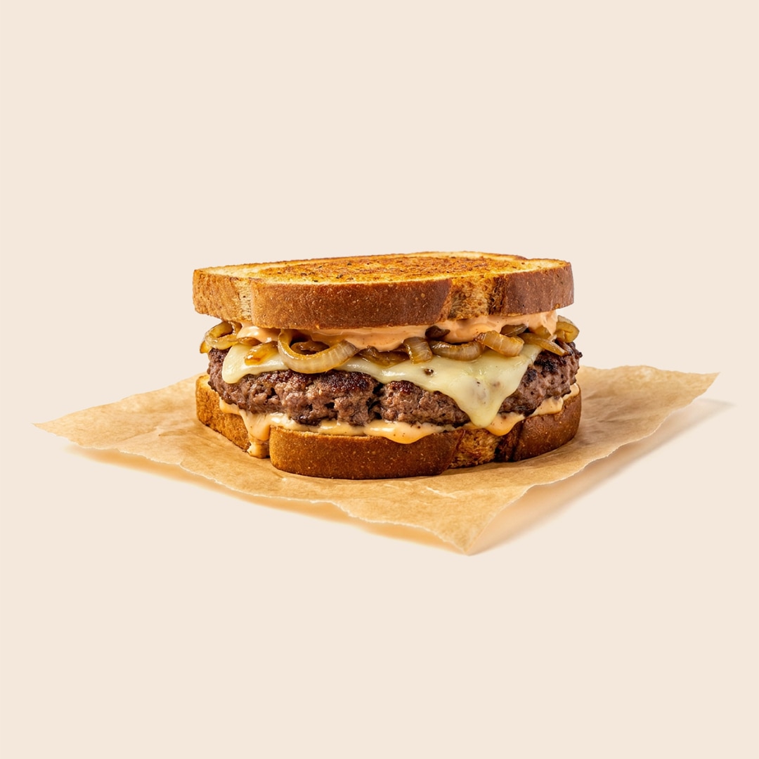 Patty melt sandwich with a beef patty, melted cheese, caramelized onions and mayo on toasted rye bread.
