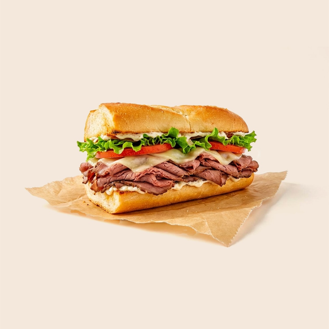 Roast beef sub sandwich with lettuce, tomato, melted cheese and mayo on a long roll.