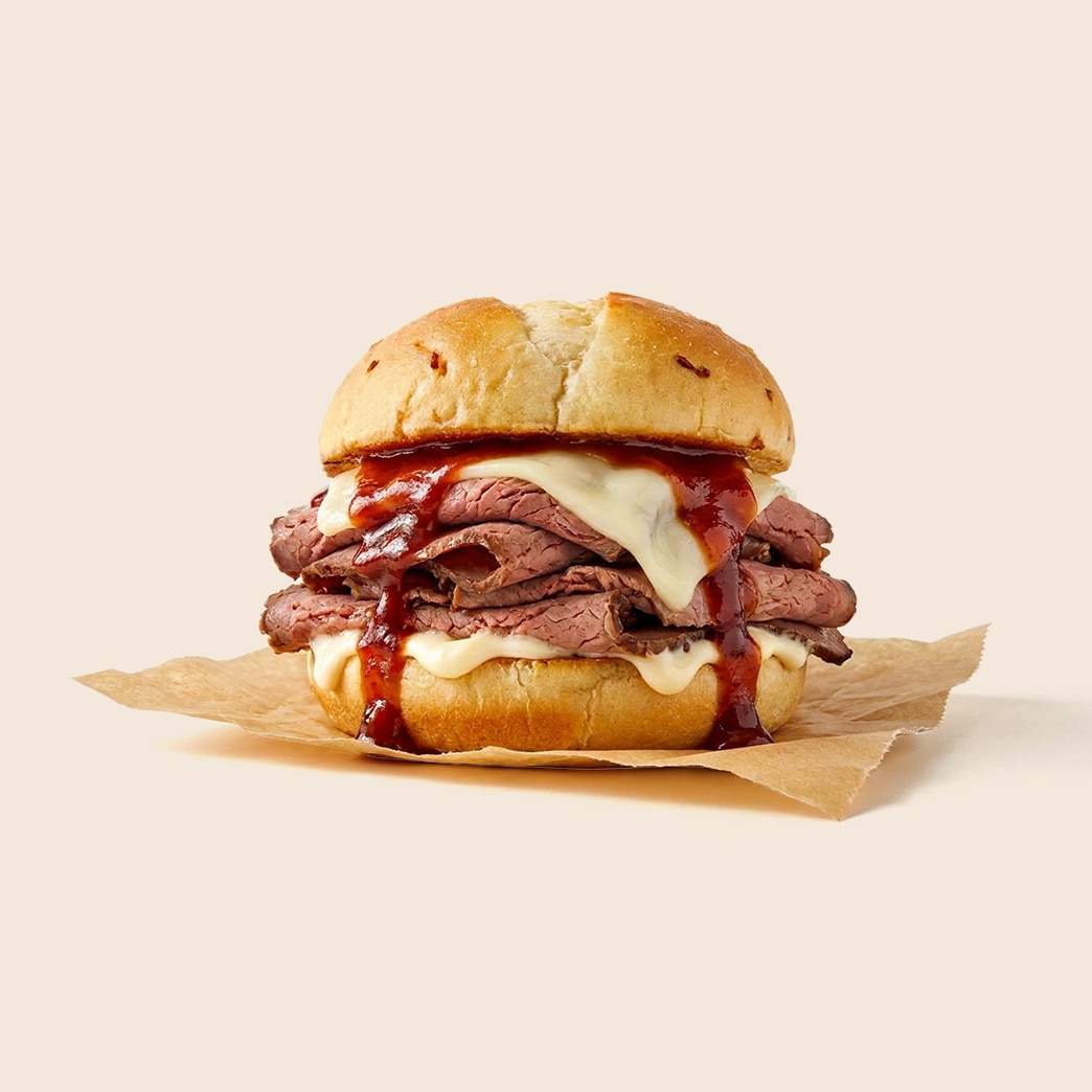 North Shore style roast beef sandwich piled high with thinly sliced beef, melted cheese, barbecue sauce and mayo on an onion roll.