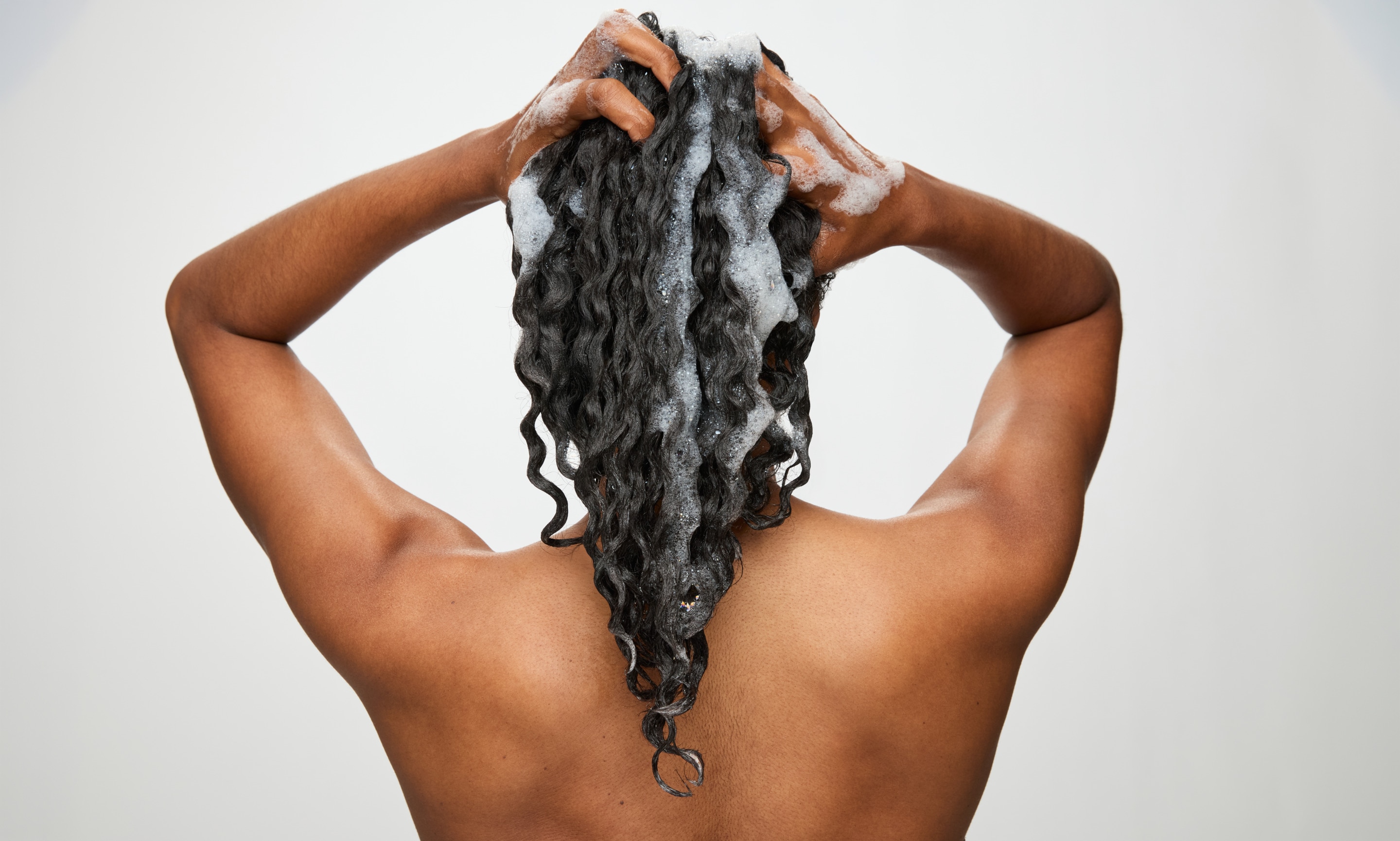Woman washing curls showing best hair shampoo and conditioner application