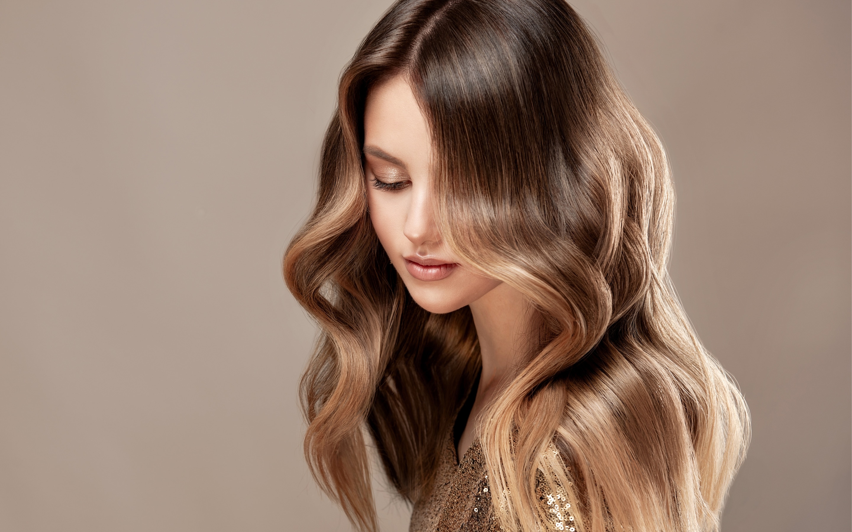 Woman with long, glossy, toffee-colored hair looking down.