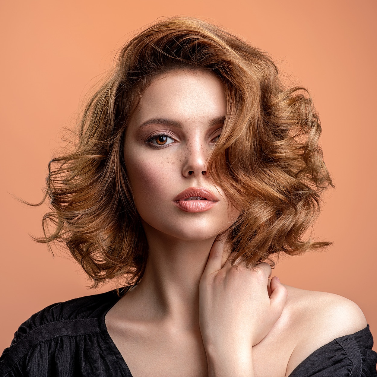 A woman with a short layered bob whose hair is fixed in soft stylish waves away from her head