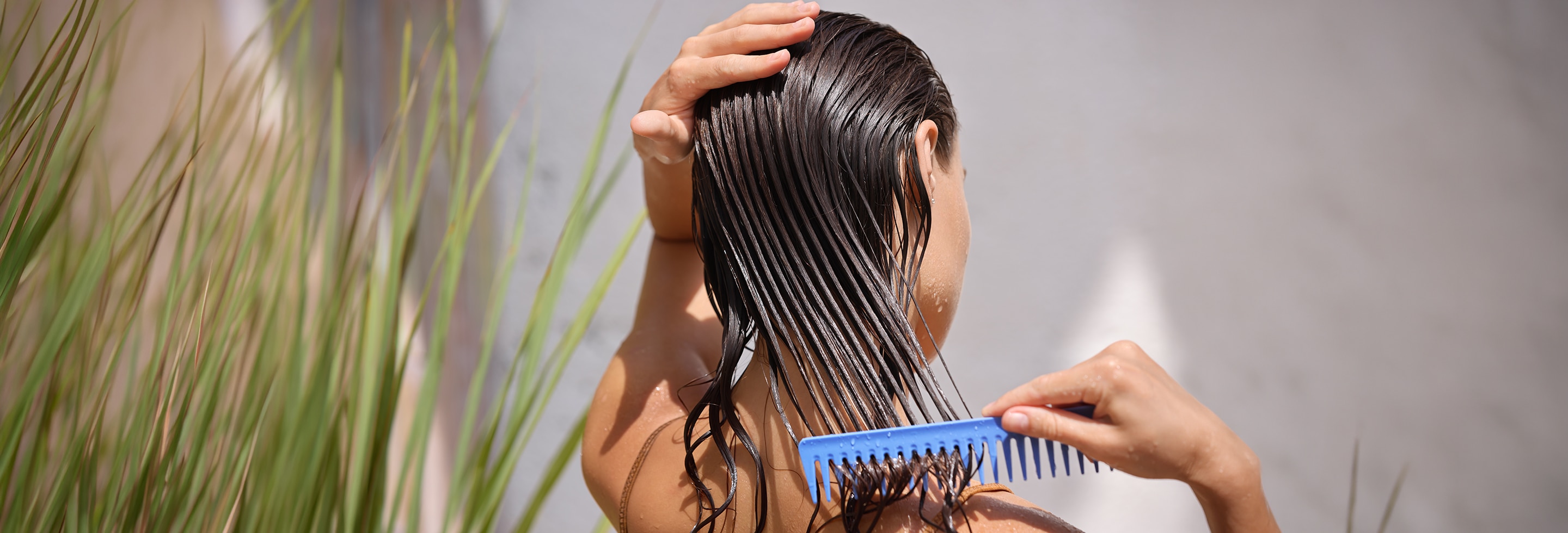 Woman combing deep conditioning mask through her wet hair