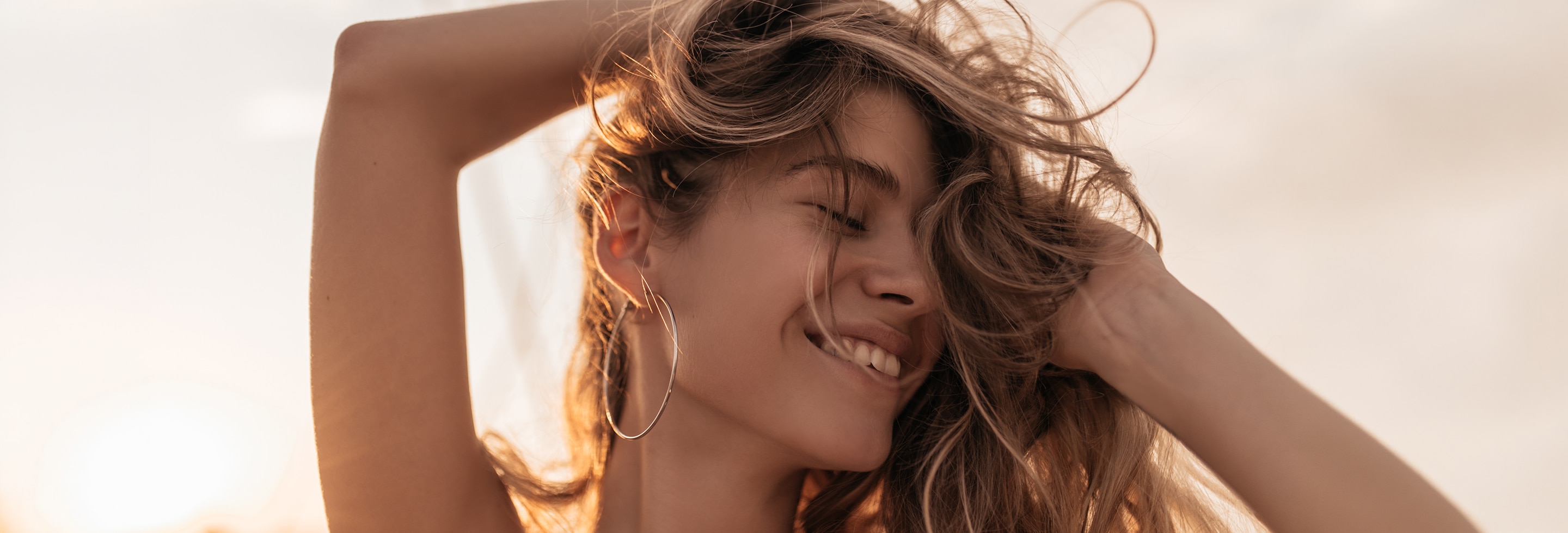 A woman in the evening sun enjoying her long messy hair