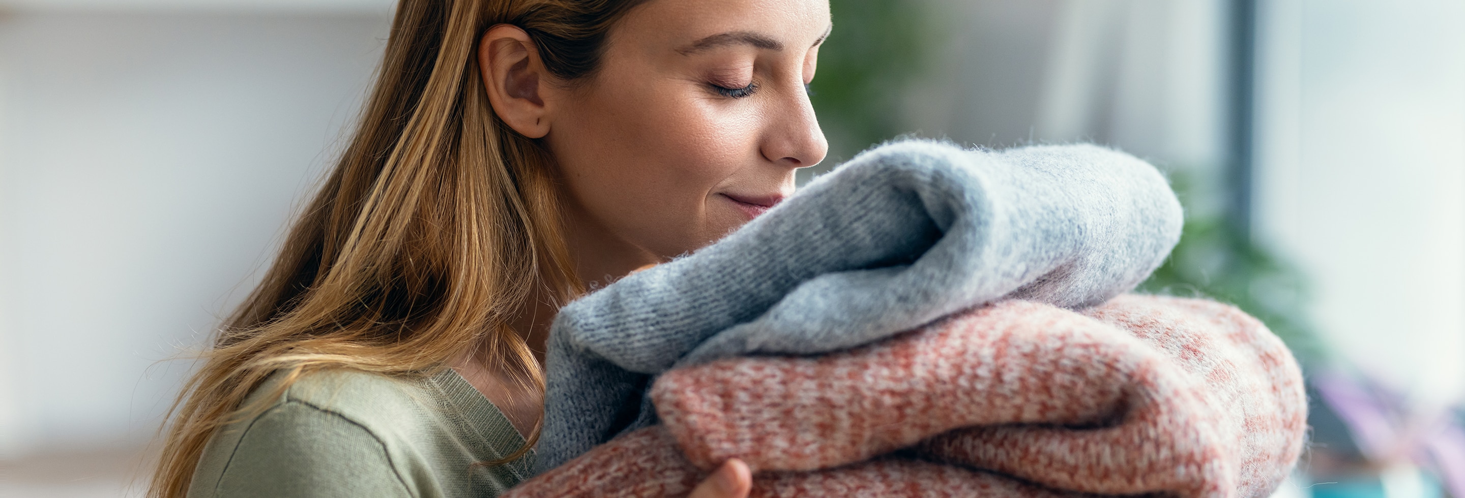 Woman holding and smelling clean clothes satisfied that she knows how to get sweat smell out of clothes.