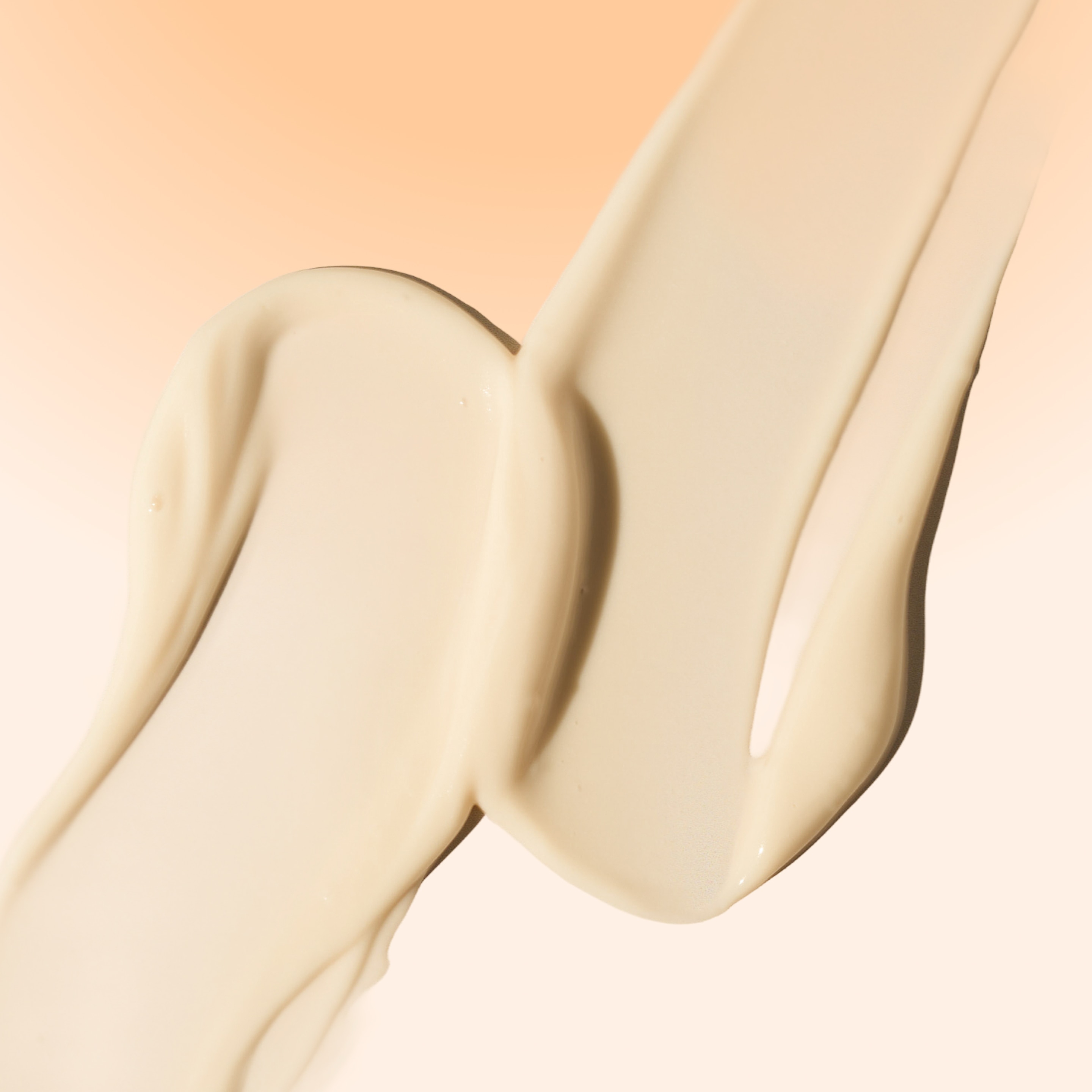 Close-up of a smooth cream-colored lotion swatch spread across a soft beige background