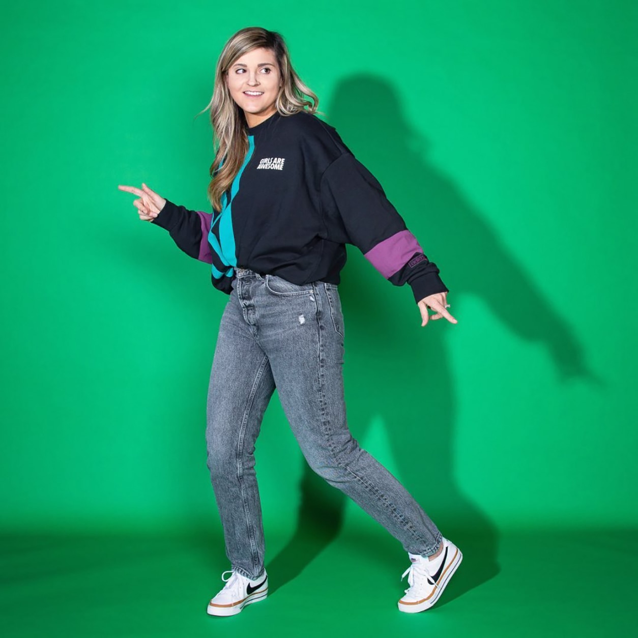 An image of a person posing with a smile and standing in front of a green background