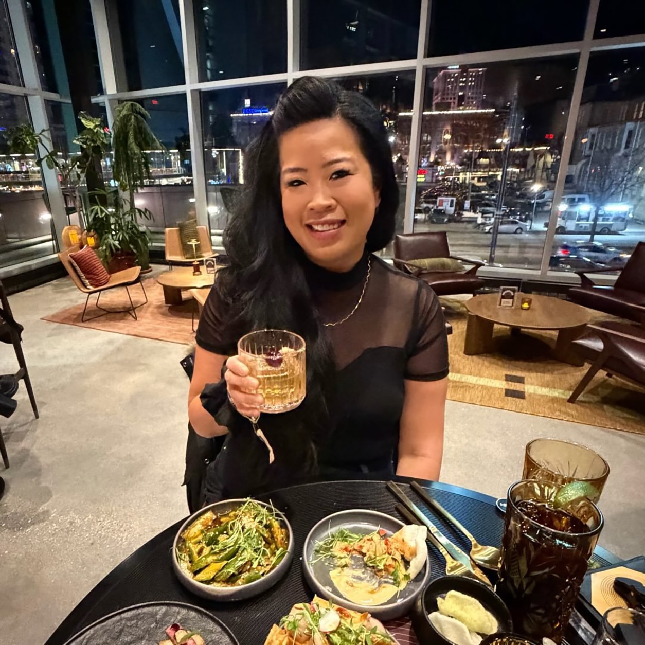An image of a person sitting at a restaurant with food and drinks on the table