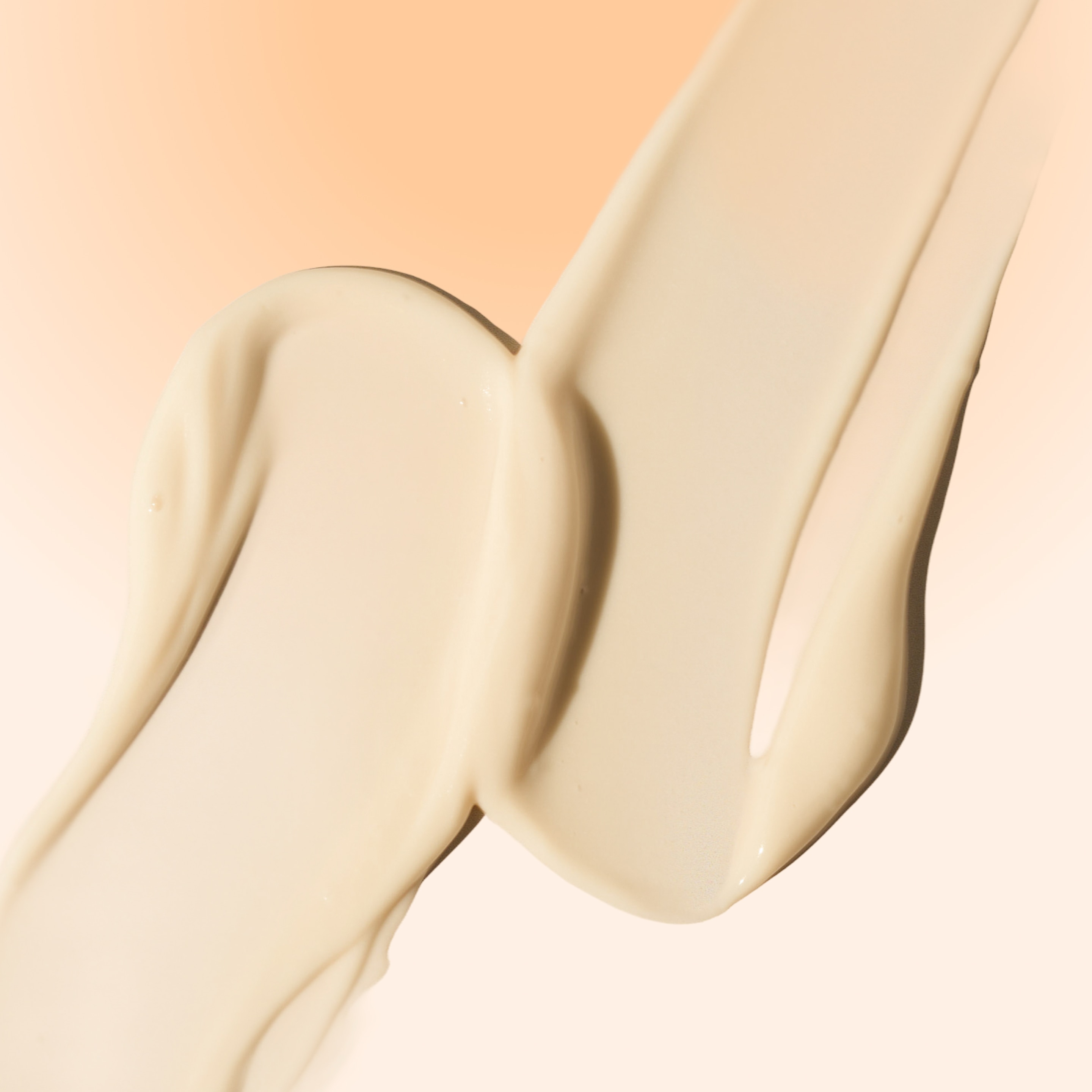 Close-up of a smooth cream-colored lotion swatch spread across a soft beige background
