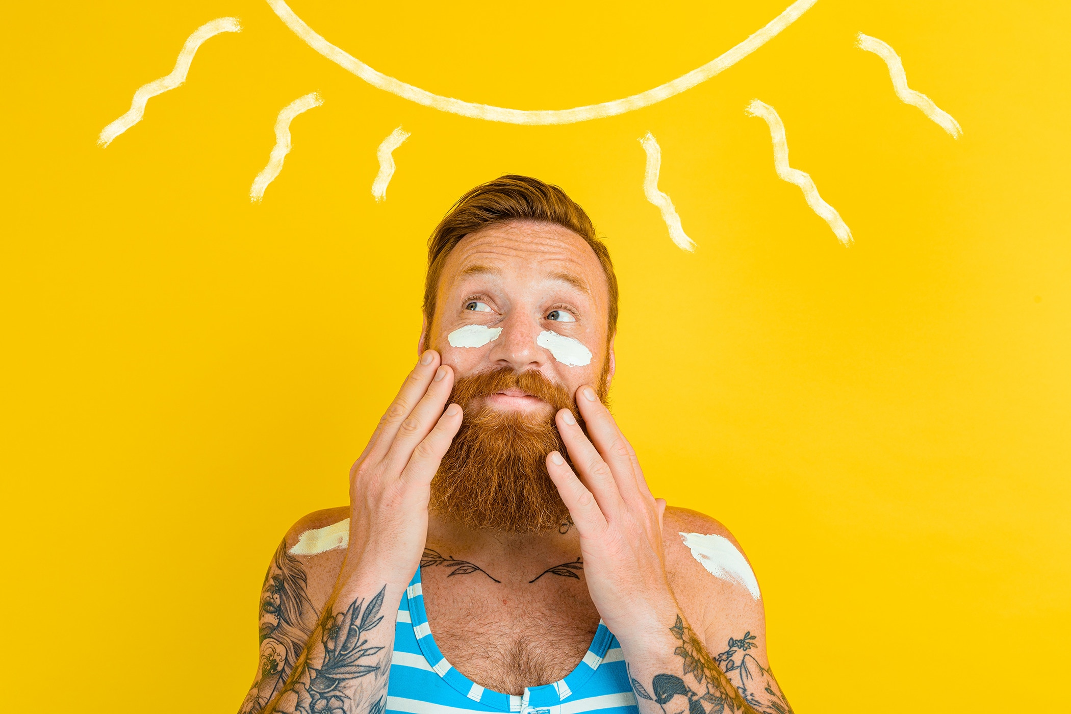 Tattooed man putting on sweatproof sunscreen
