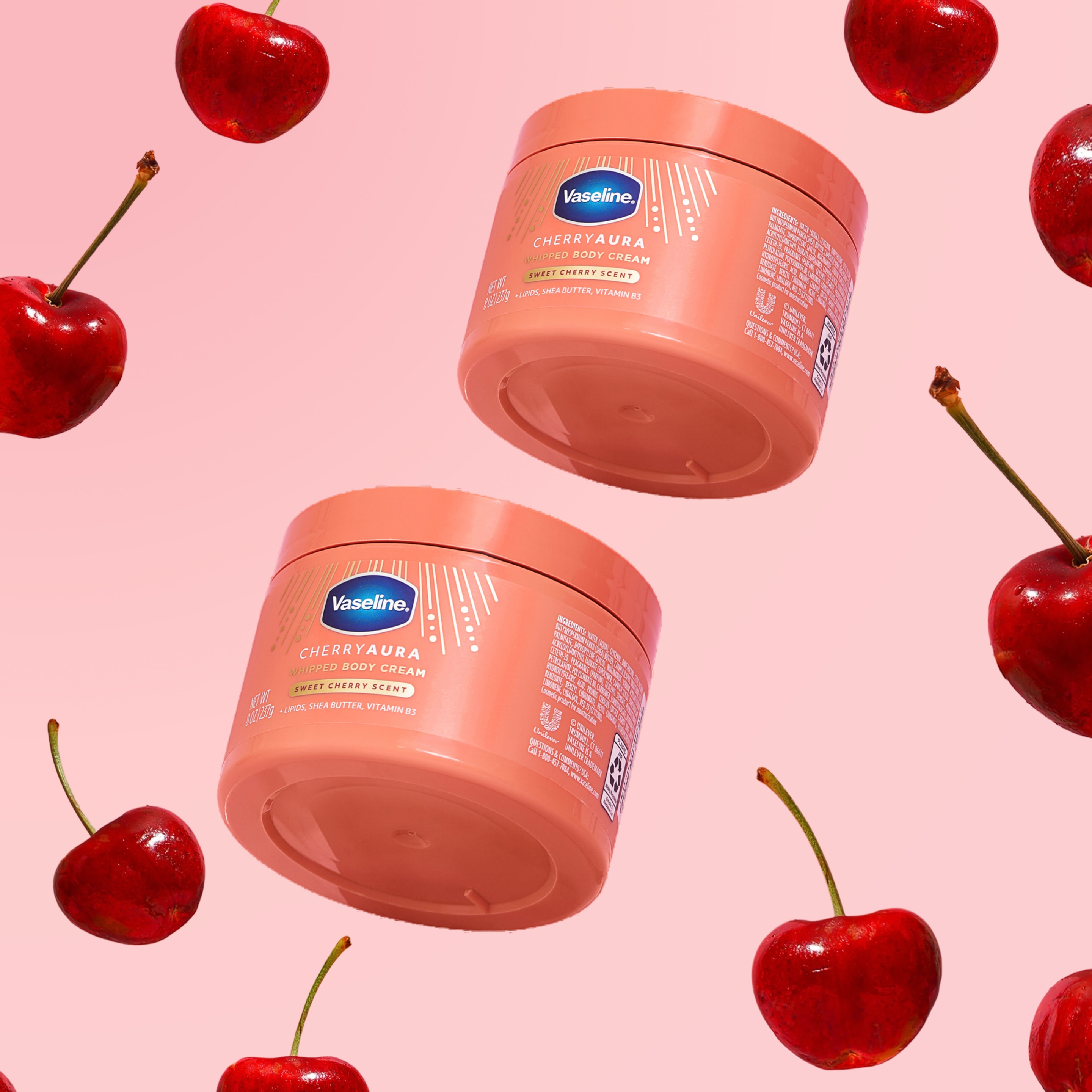 Two jars of Vaseline Cherry Aura Whipped Body Cream float among bright red cherries