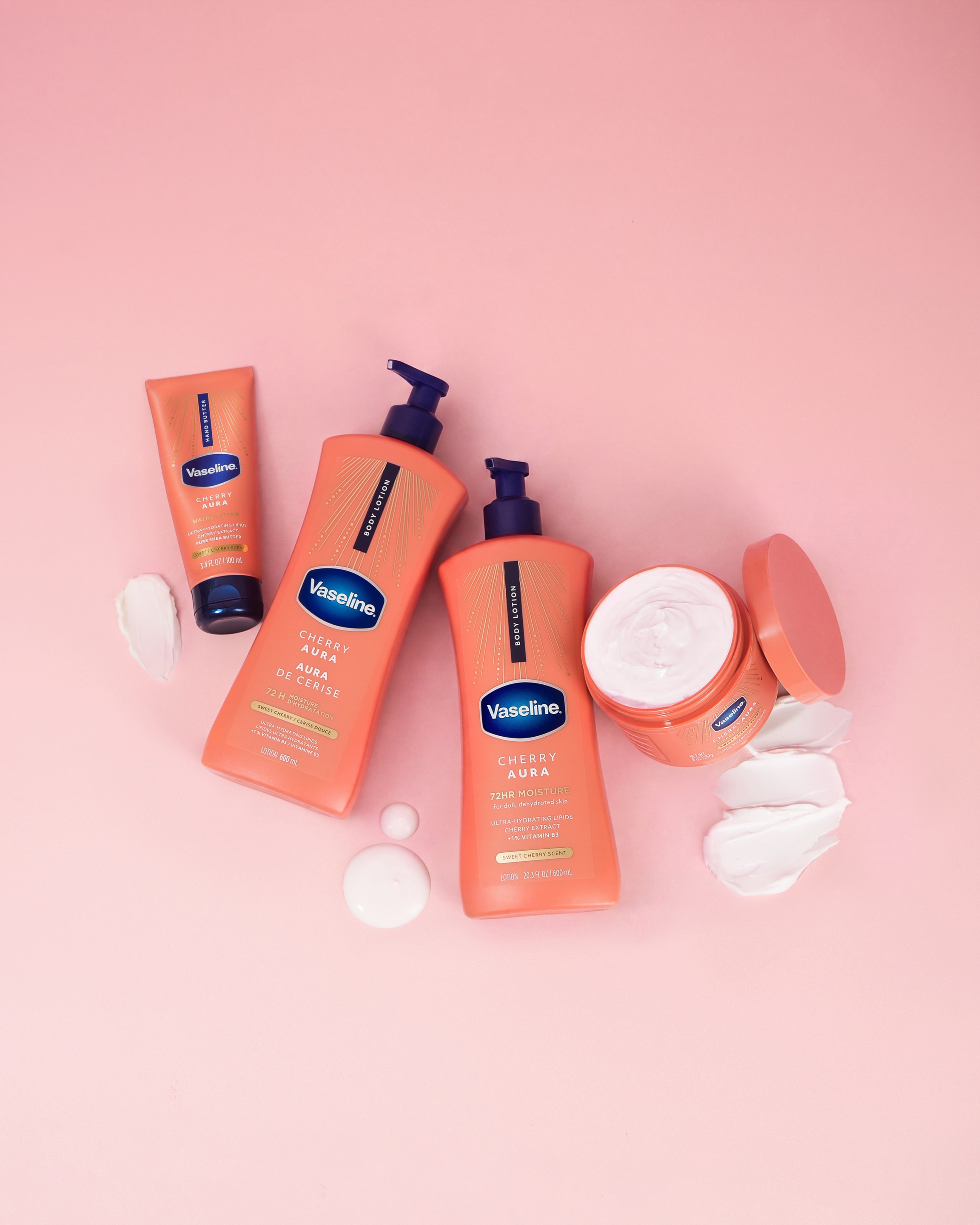 Vaseline Cherry Aura body care range, including body lotion, hand butter, and body cream, displayed on a pink background with cream swatches.