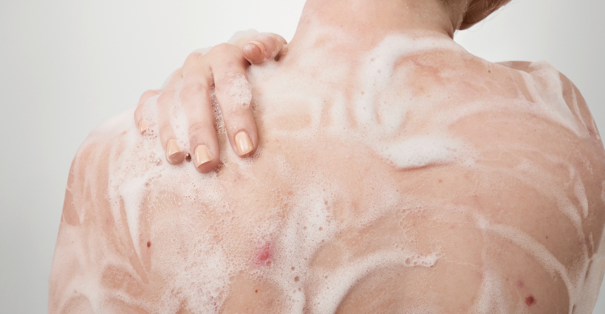 Lifestyle image, woman using Dove body wash in the shower