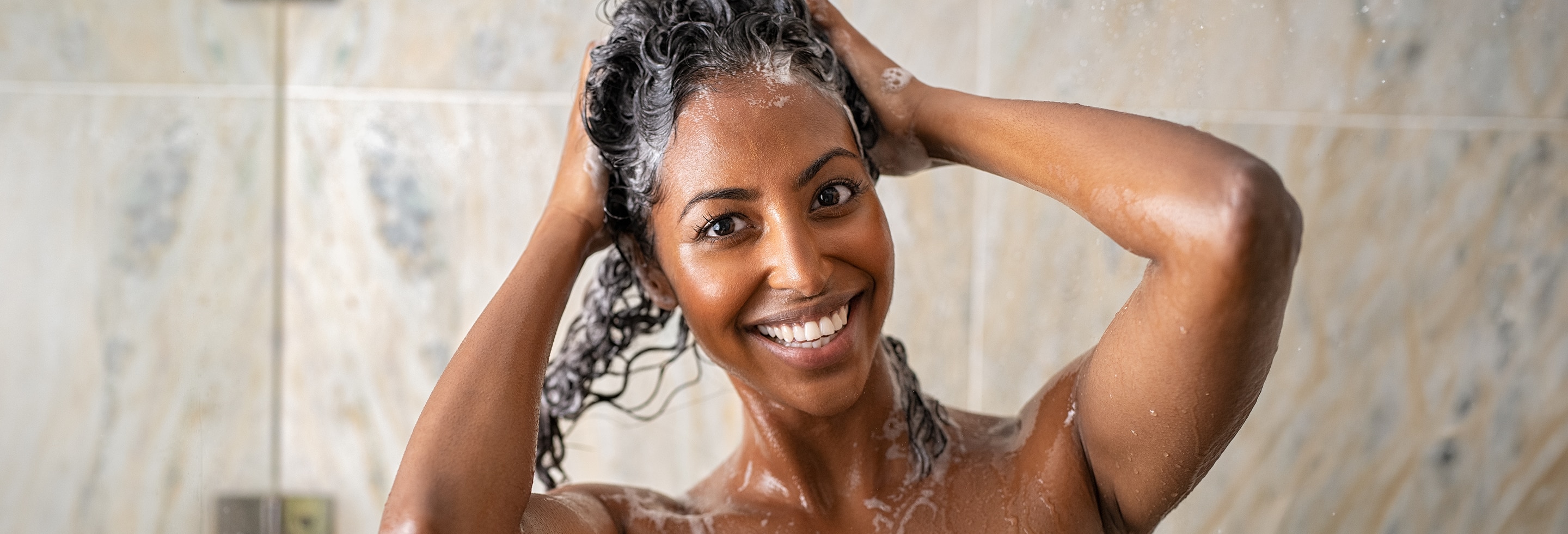 Happy woman in the shower who knows how often her hair needs washing.
