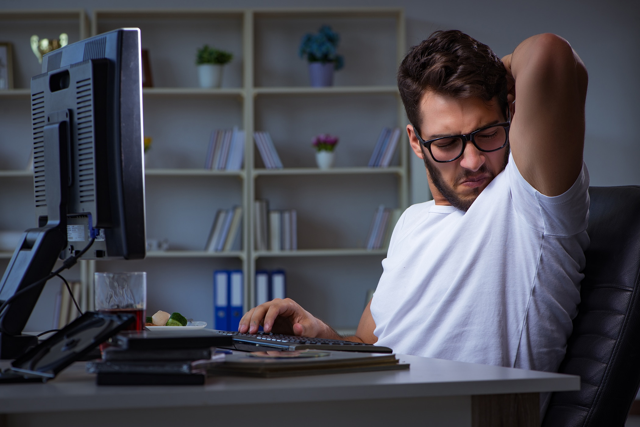 Man in an office smelling his armpit after trying to neutralize odor