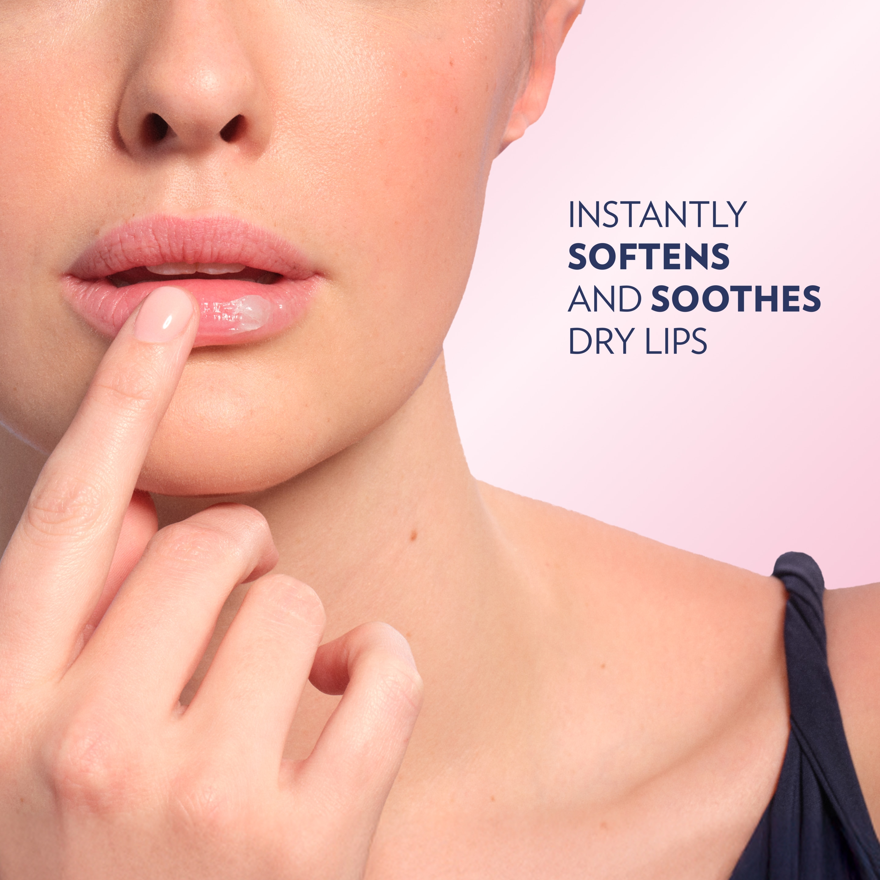 Close-up of a person applying Vaseline lip balm to their lips with a fingertip against a pink background, with text