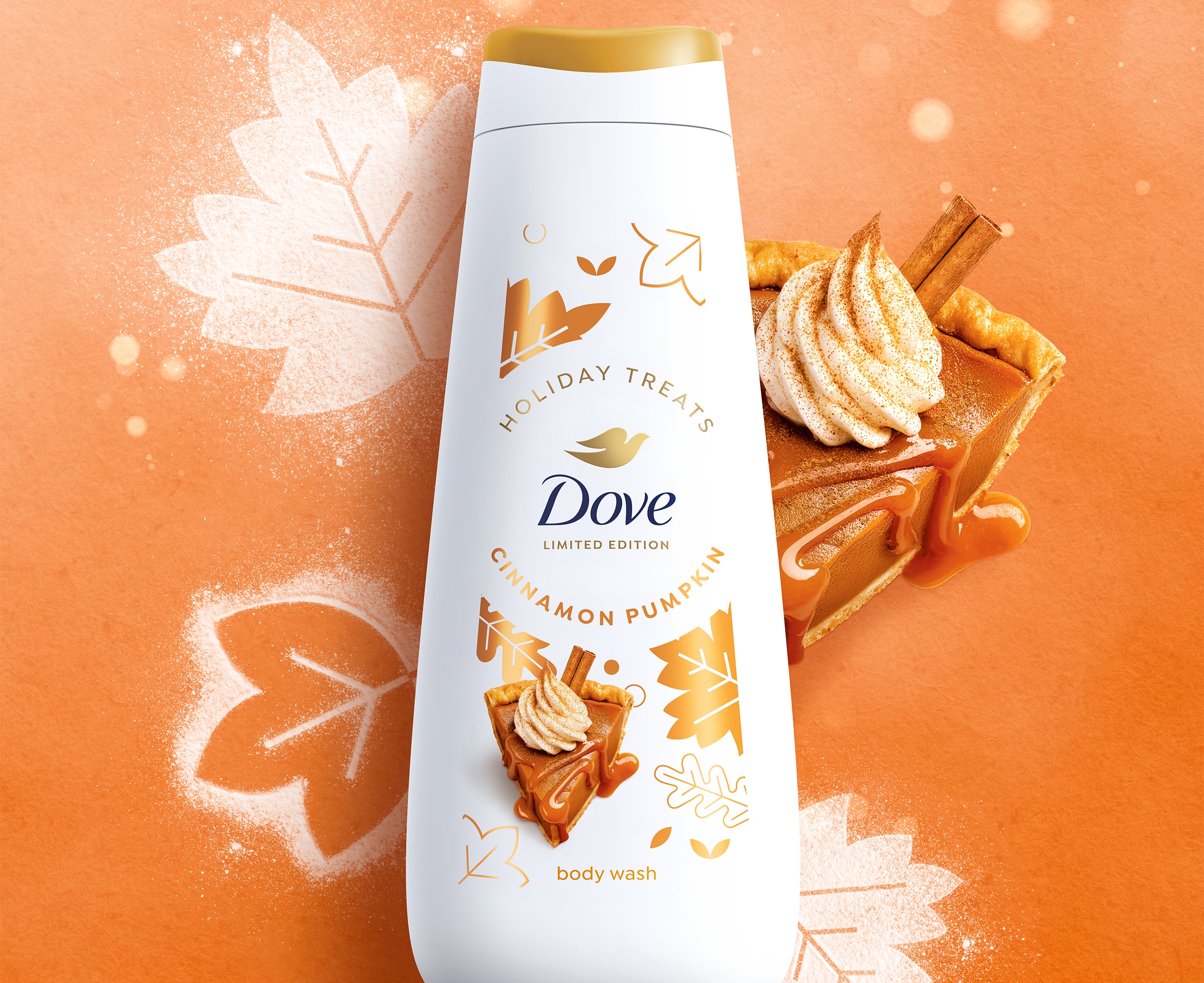 Dove Holiday Treats Cinnamon Pumpkin Body Wash pack laying against an orange background with ice sugar leaves behind it along with a slice of pumpkin pieDove Holiday Treats Cinnamon Pumpkin Body Wash pack laying against an orange background with ice sugar leaves behind it along with a slice of pumpkin pie