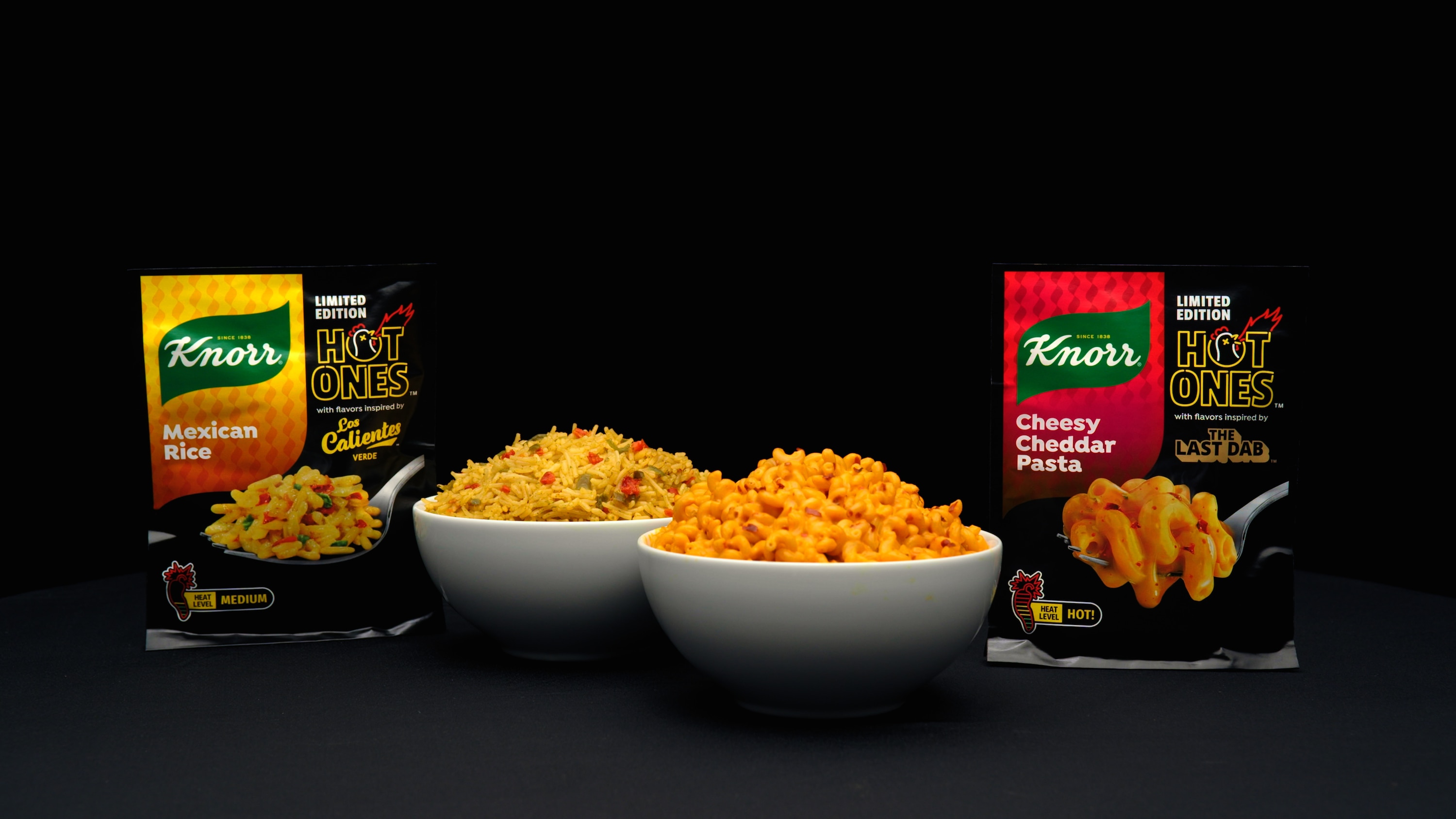 Knorr x Hot Ones limited edition Mexican Rice and Cheesy Cheddar Pasta products displayed with prepared rice and pasta dishes.
