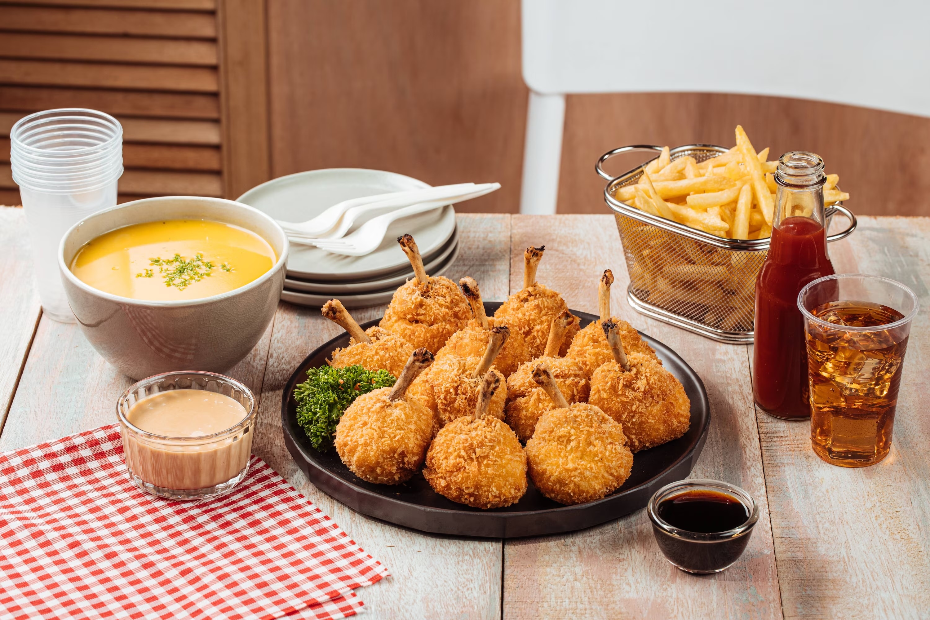 A plate of chicken lollipops served with fries and dipping sauce.