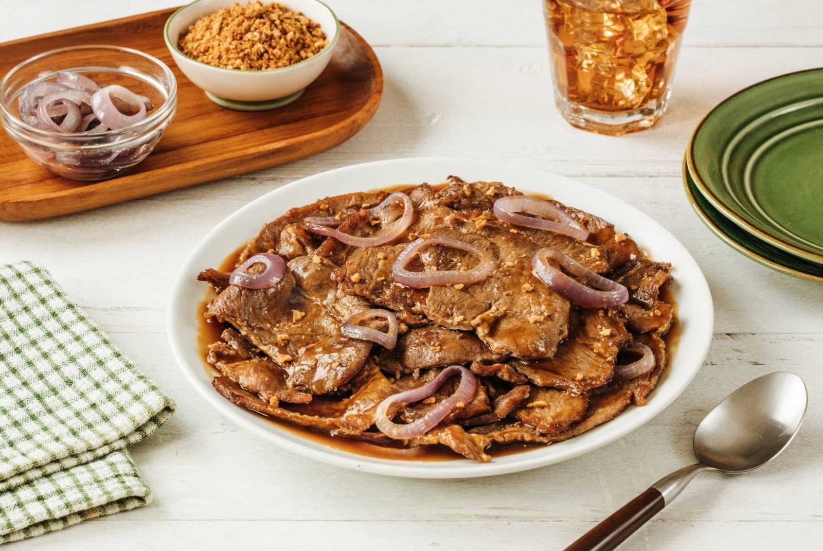 Bistek Tagalog topped with fried garlic and red onions.