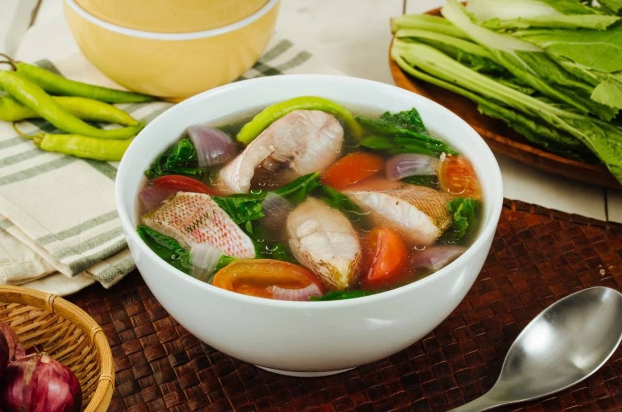 Sinigang na maya-maya with tomatoes, onions, fresh greens, and chilies.
