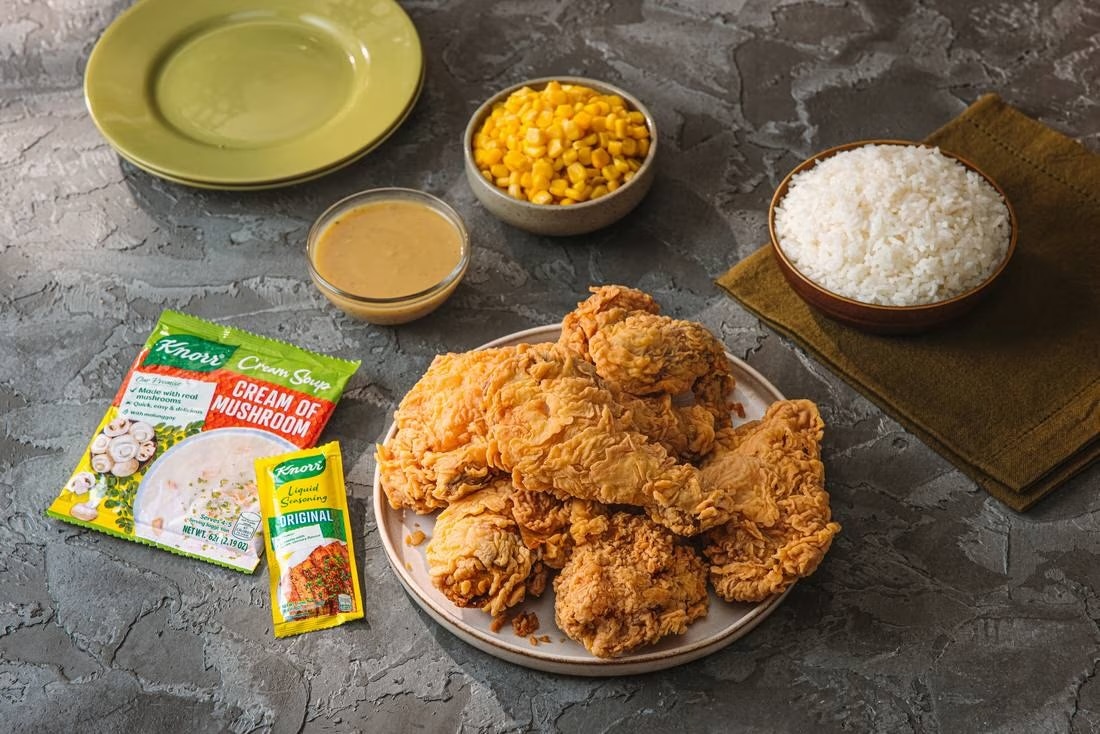 Fried chicken served with corn, rice, and gravy.