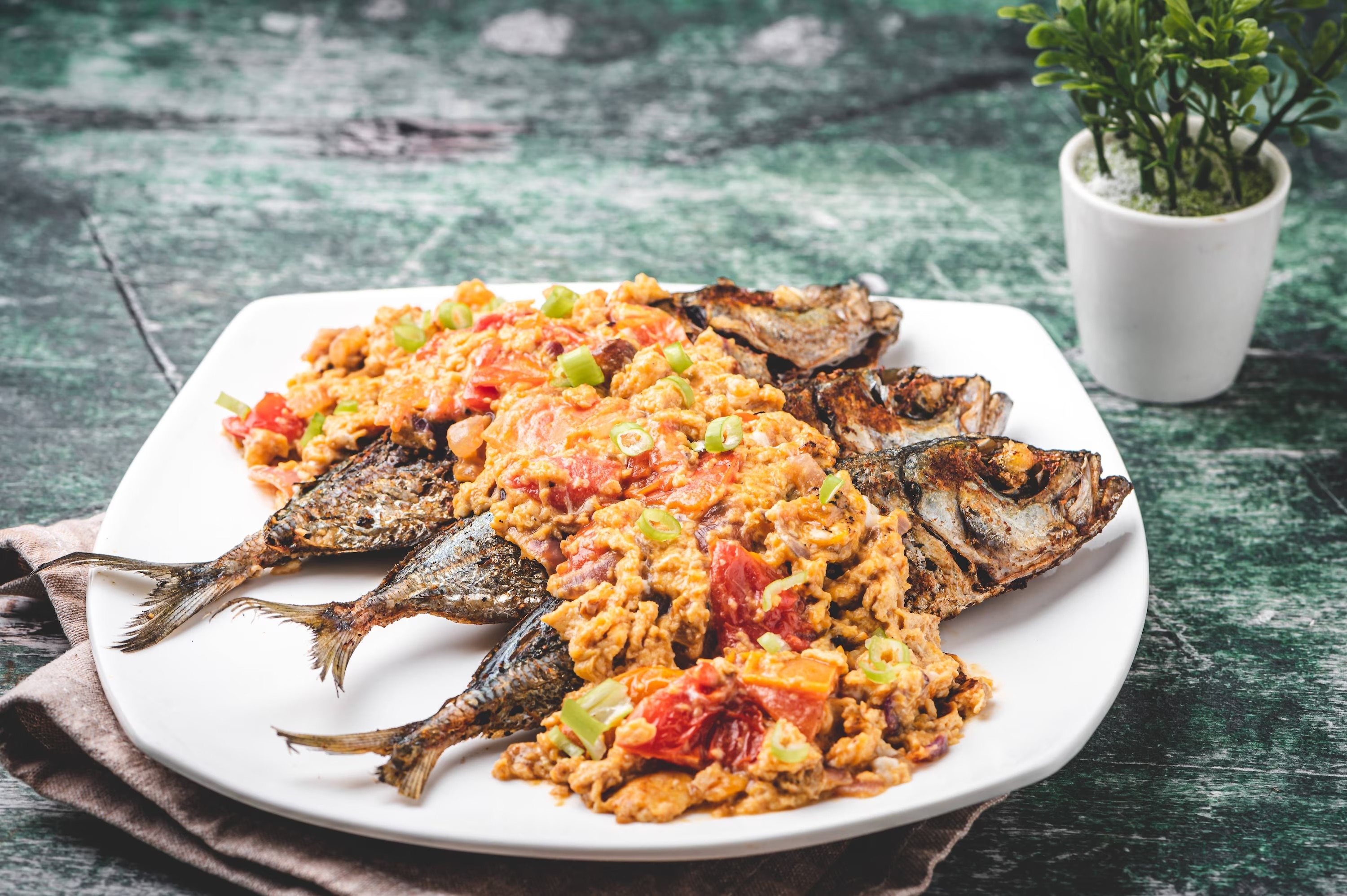 A plate of fried fish topped with sarciado sauce.