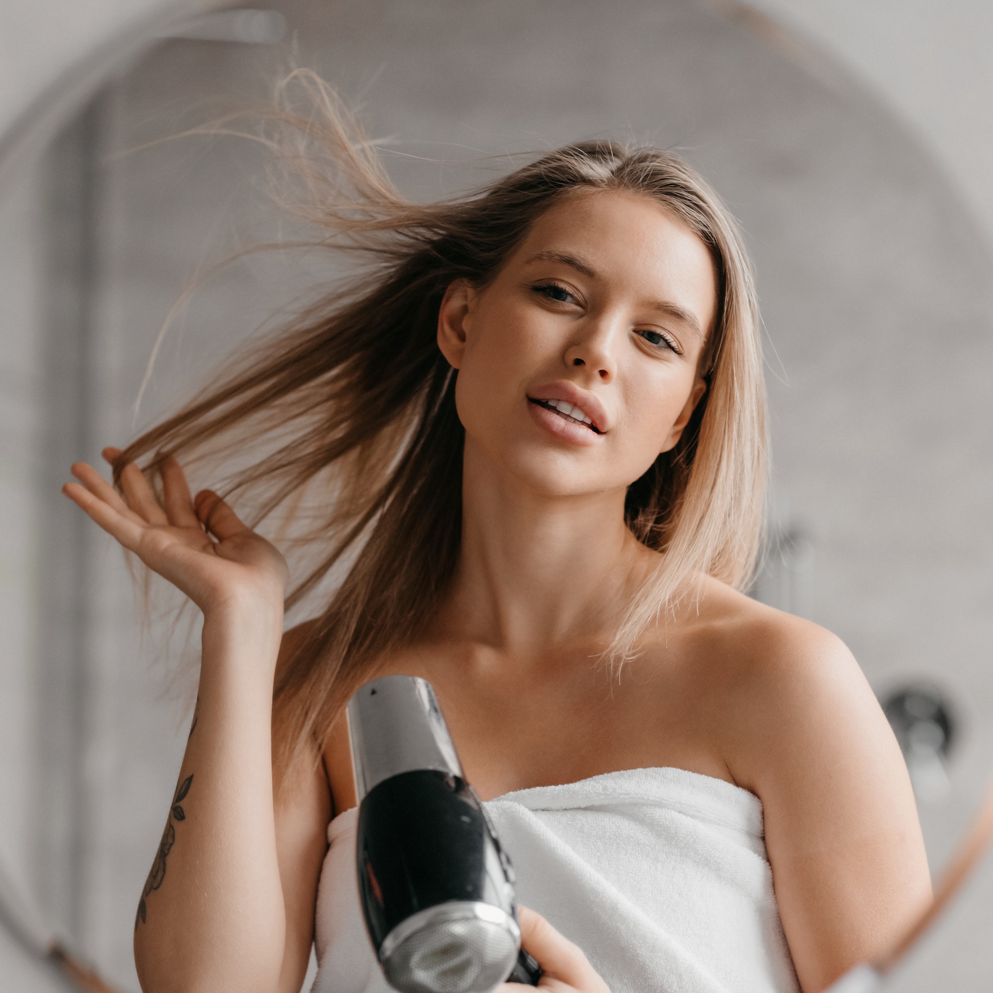 Woman blow-drying her hair in the mirror