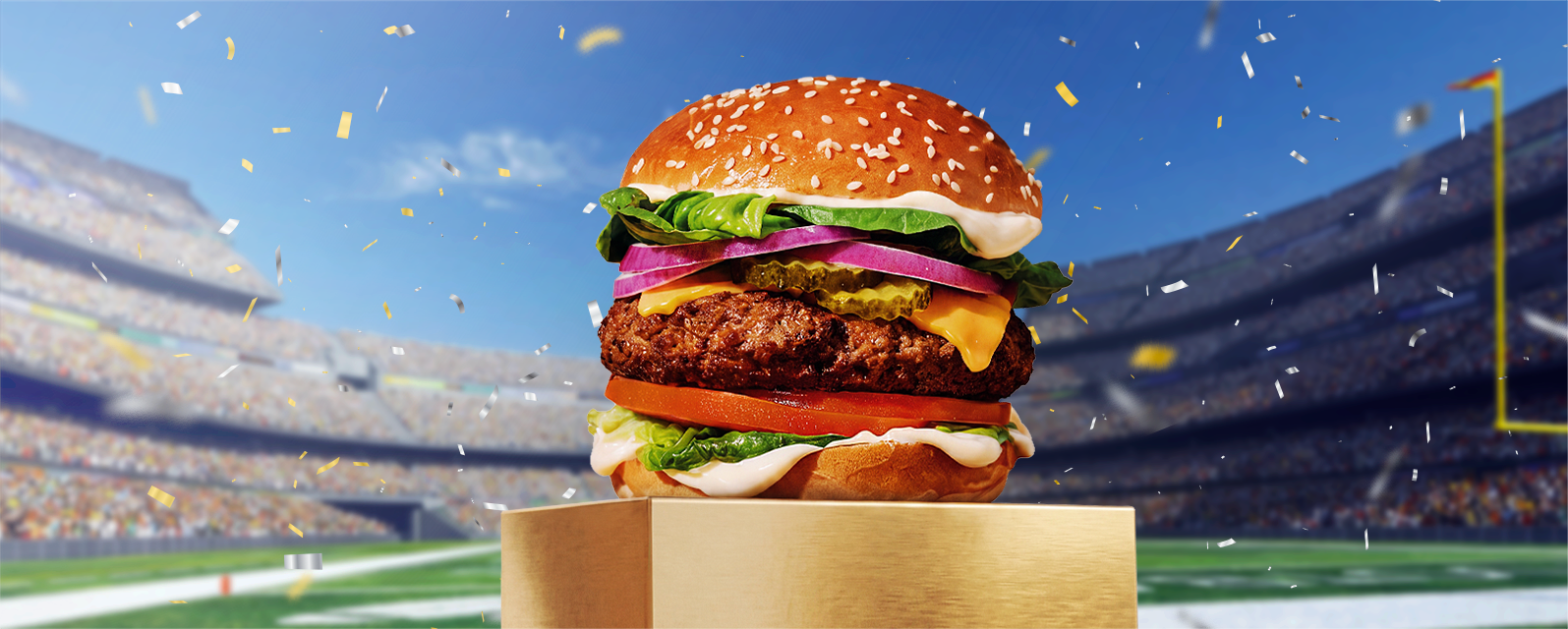 Cheeseburger with melted cheese and fresh toppings displayed in a football stadium.