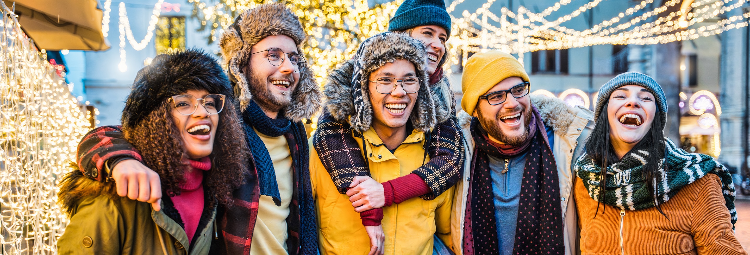 Group of friends staying fresh and confident at an outdoor holiday market surrounded by festive lights