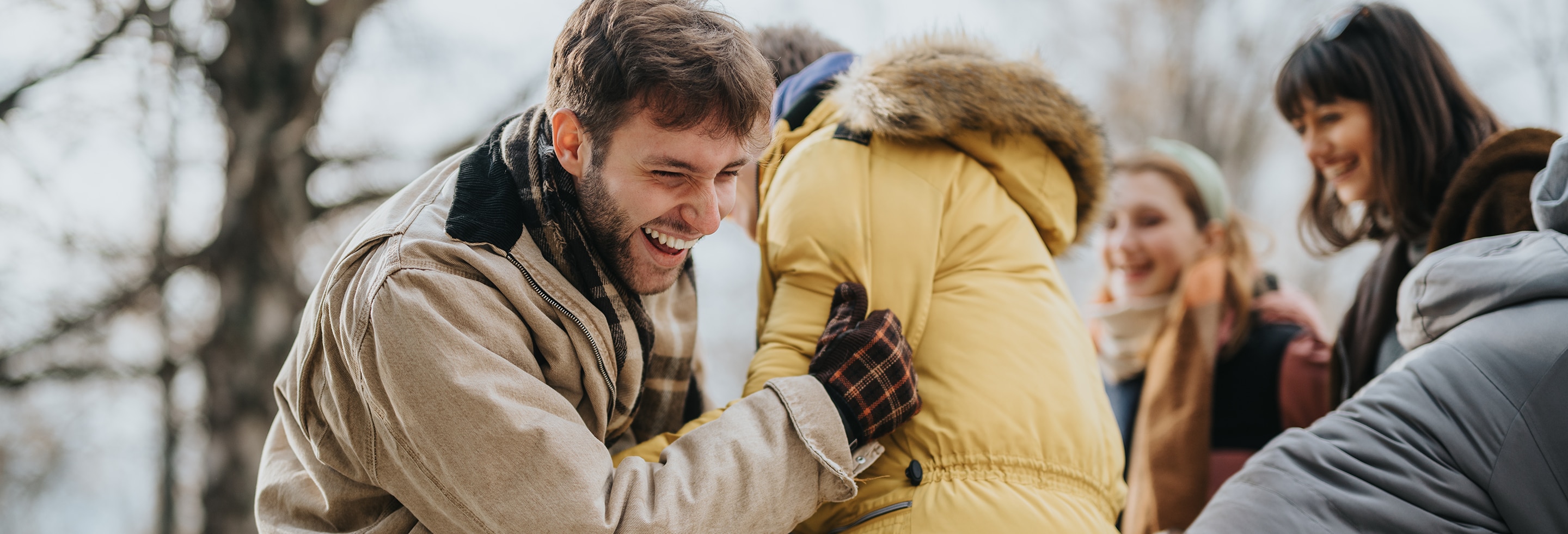 Man staying fresh while laughing and hugging friends outdoors in cold weather