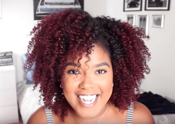 woman with natural black hair styling her hair by twisting small sections