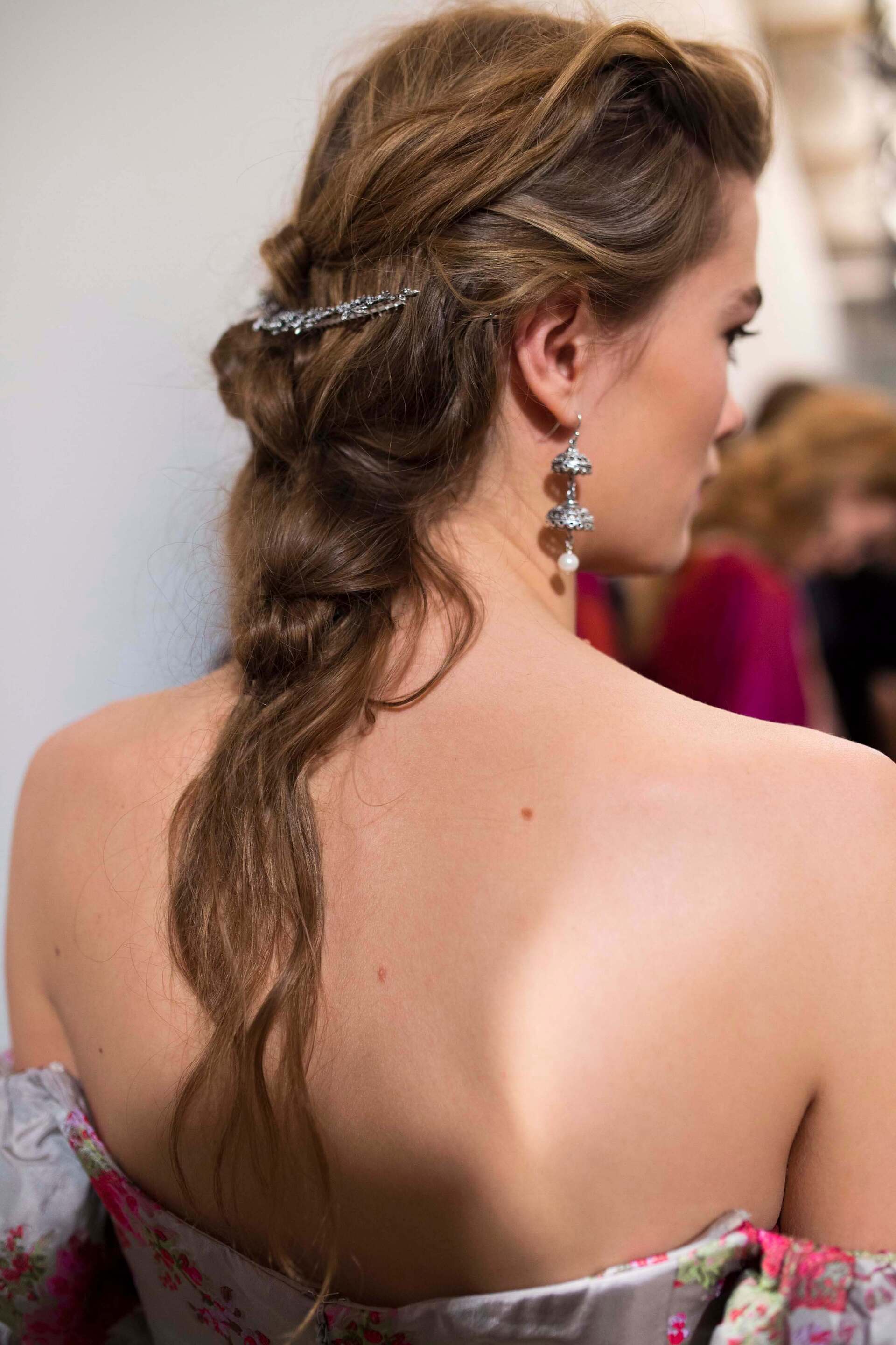 Gibson girl hair: Image of a woman in a wedding dress looking in the mirror with blonde hair and a gibson tuck hairstyle