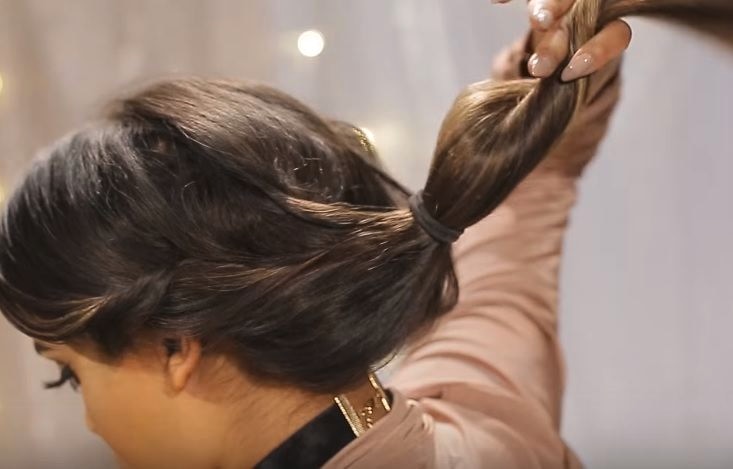 Gibson girl hair: Back view of a woman with pink and black hair in a loose gibson tuck hairstyle with pearl accessories