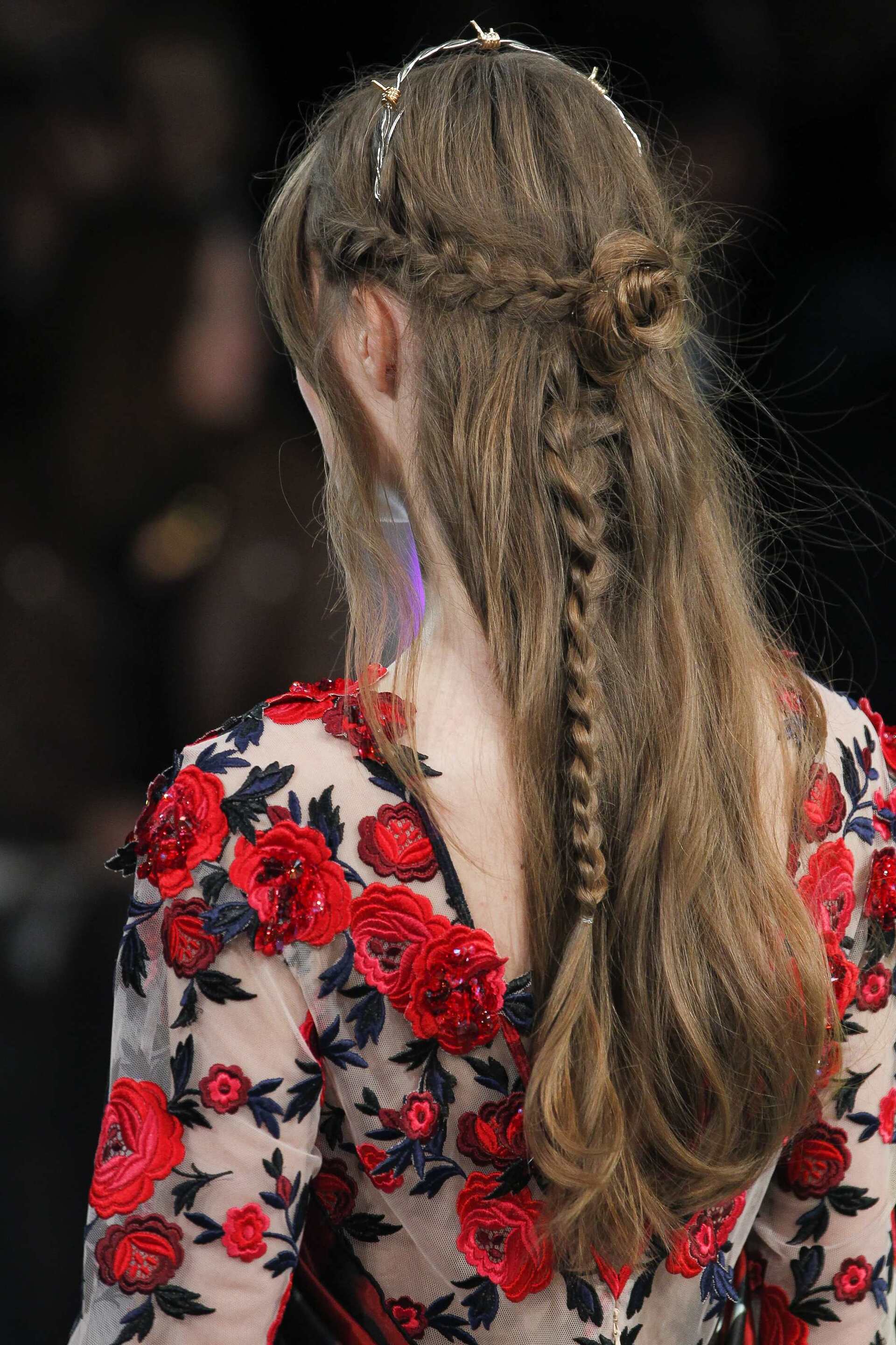 Half up half down wedding hairstyles: Woman with long bleach blonde curly styled into a half-up bun, posing outside.