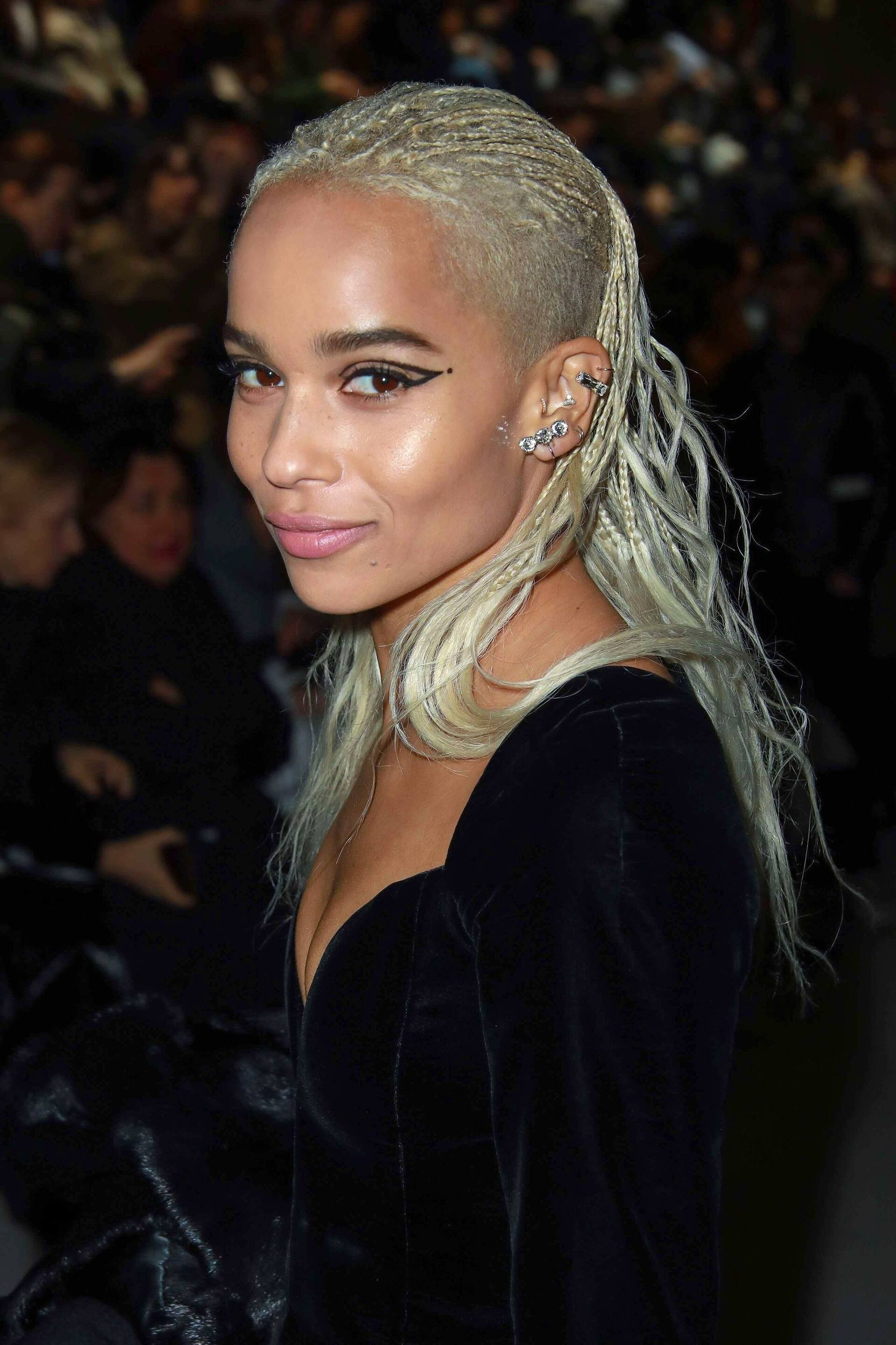 Woman with medium brown, long-layered choppy bob with blonde highlights wearing a black top.