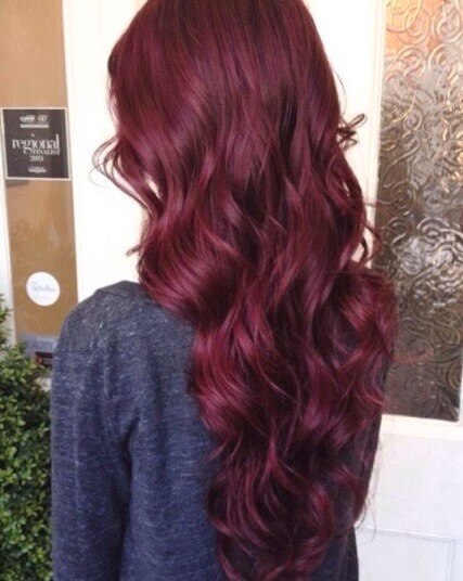 back view of a woman with really long curled burgundy hair