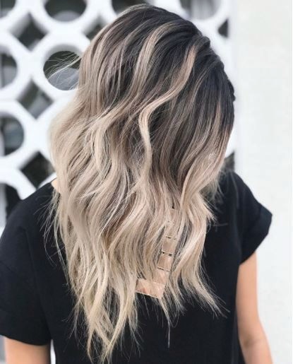 side view of woman with medium length wavy dark brown to blonde ombre