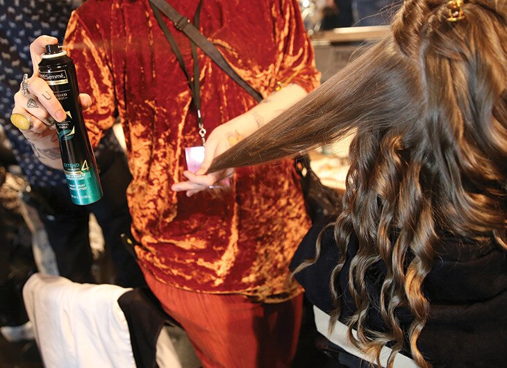 A stylist working on a model's hair backstage.