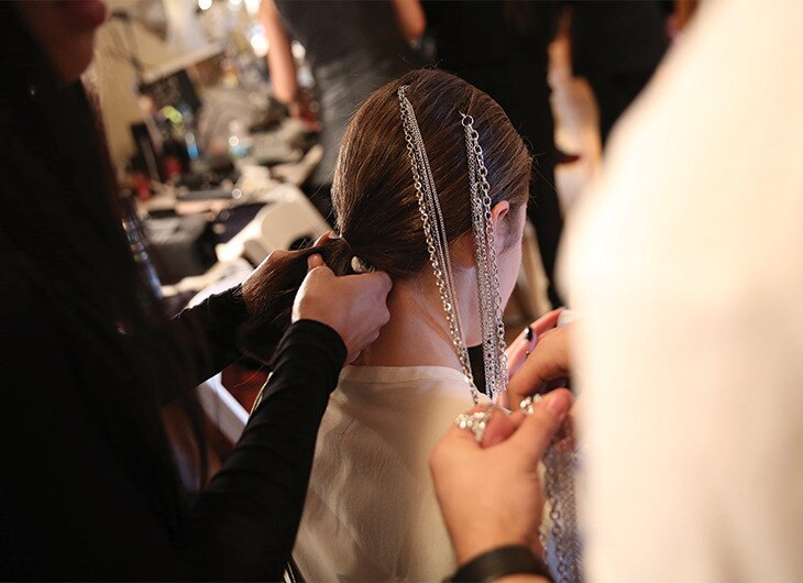 A stylist working on a model's hair backstage.