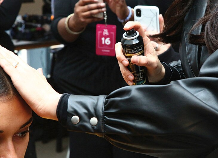 A stylist working on a model's hair backstage.
