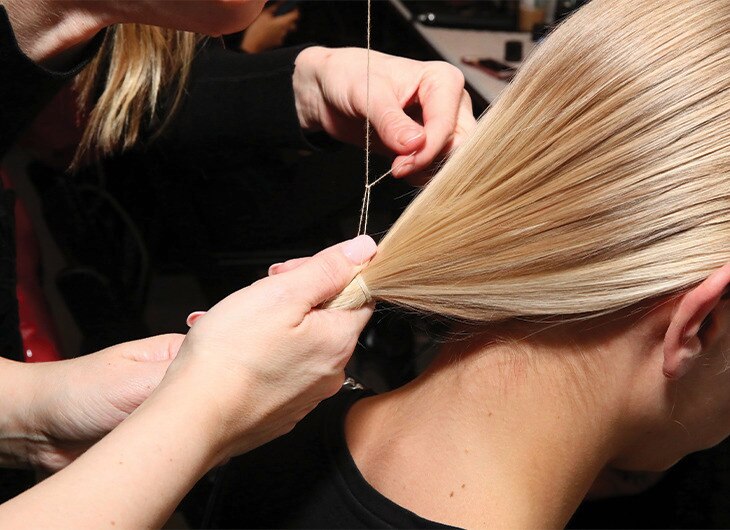 A stylist working on a model's hair backstage.