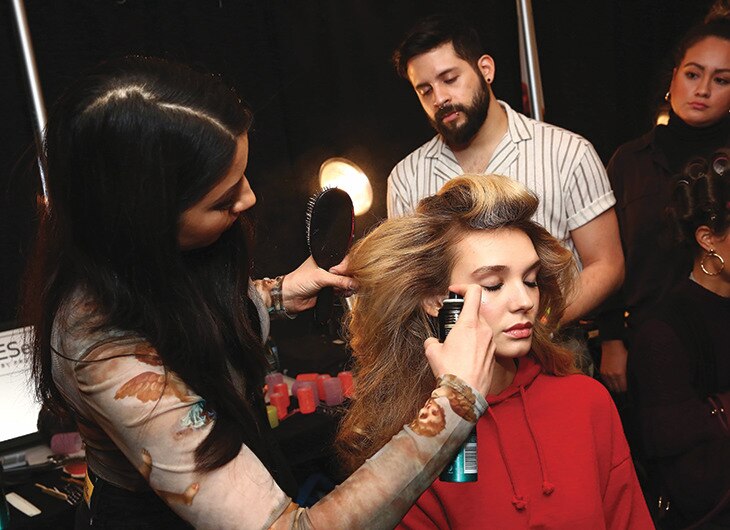 A stylist working on a model's hair backstage.