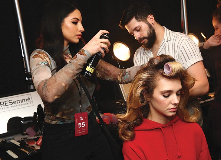 A stylist working on a model's hair backstage.