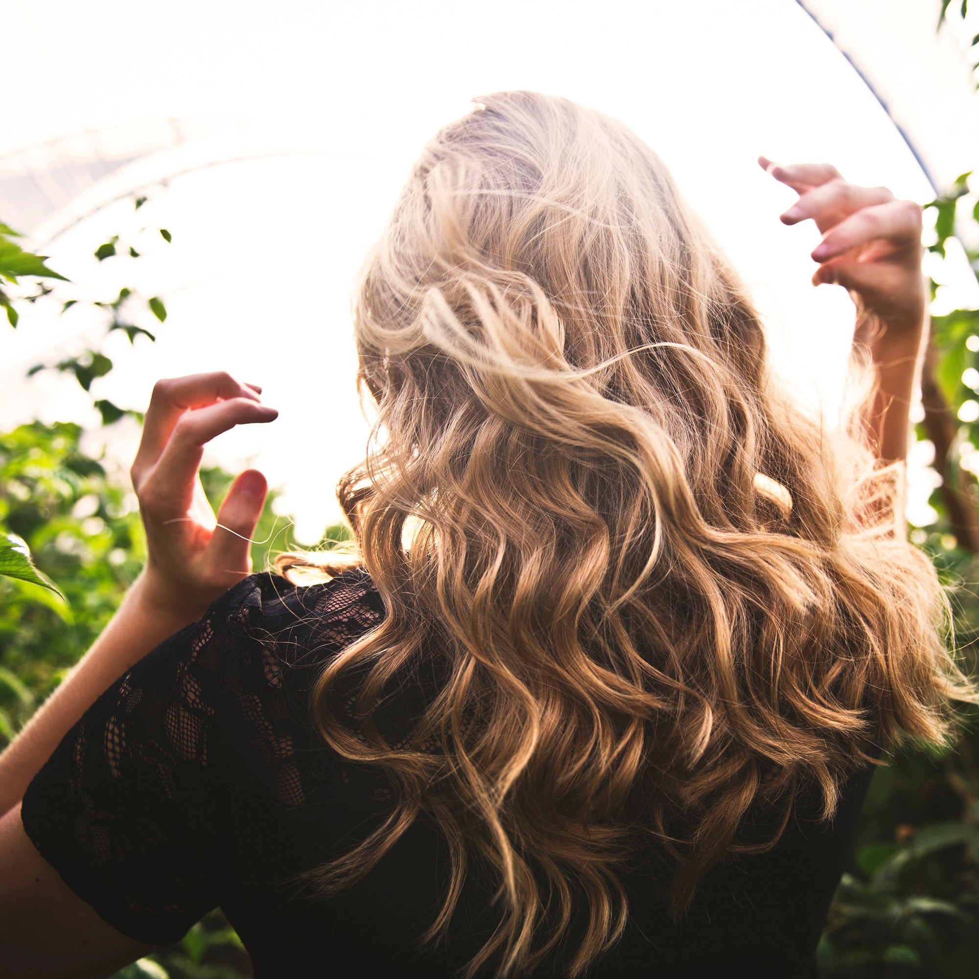 side view of woman with half up crown braid with two white flowers placed in the braid