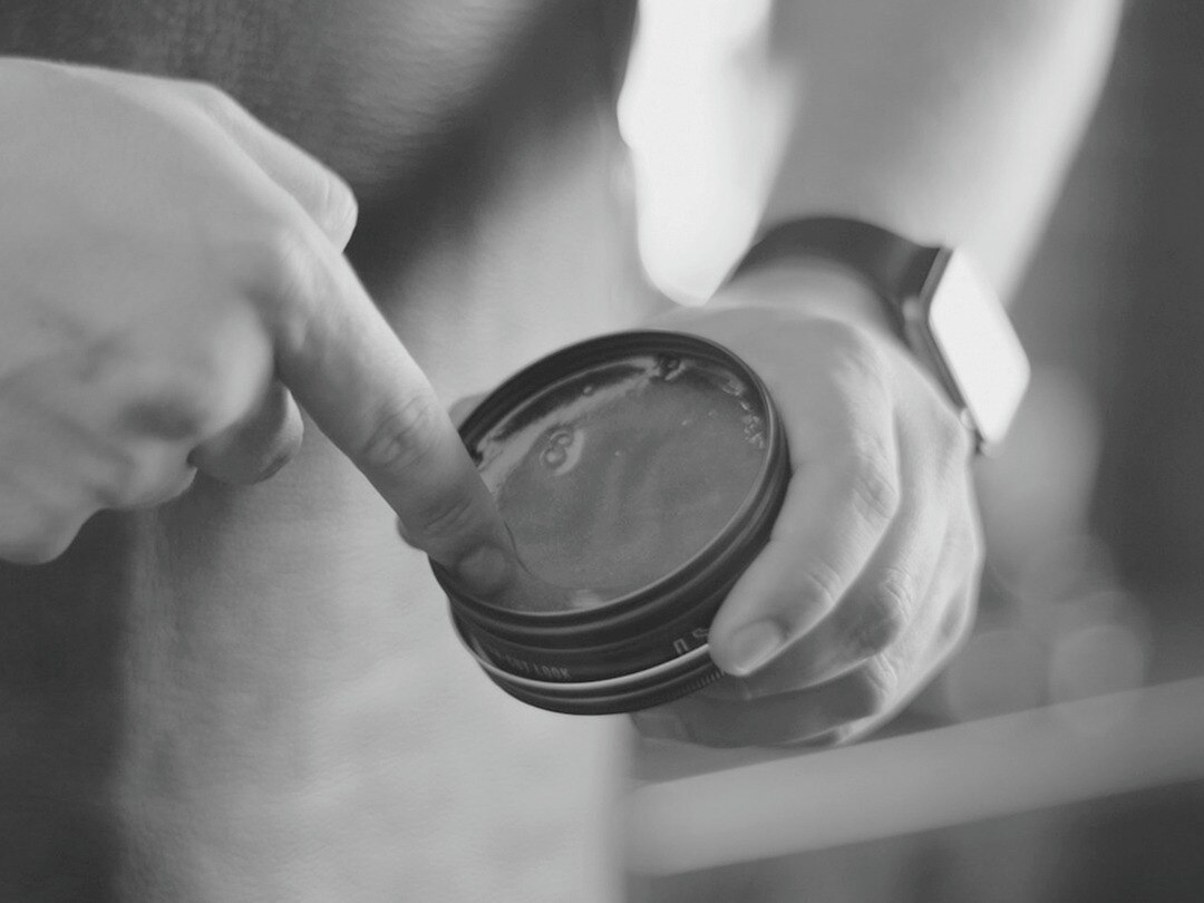 A guy brushing his hair in to a quiff.