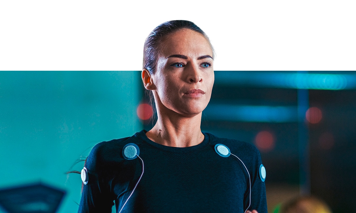 Mujer de ojos azules haciendo ejercicio con electrodos de estimulación muscular en la camiseta