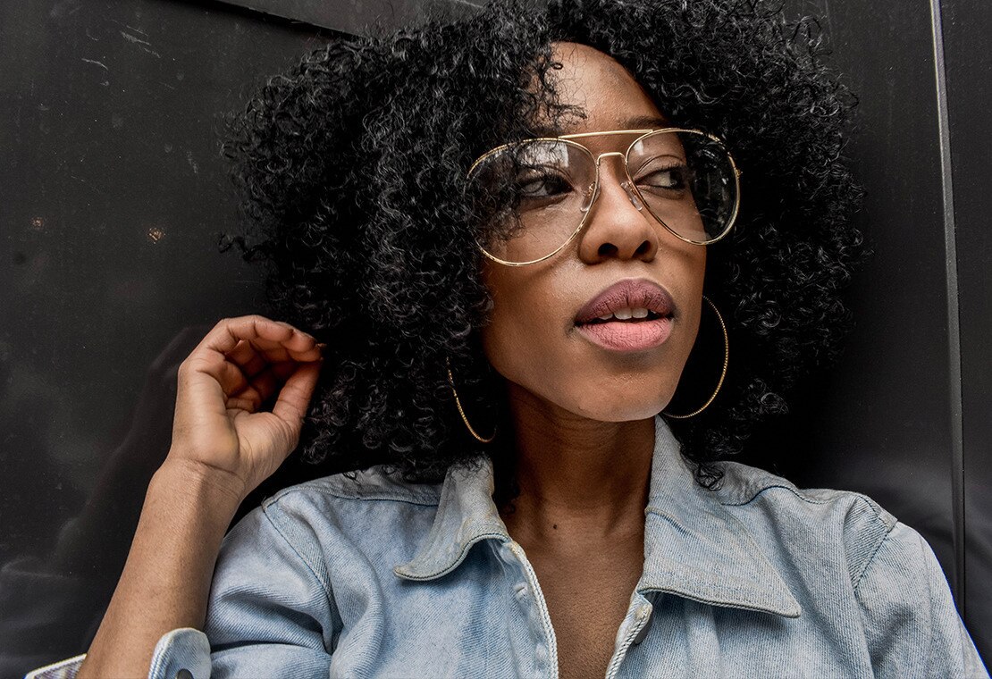 Black woman with coily hair wearing glasses and a denim jacket