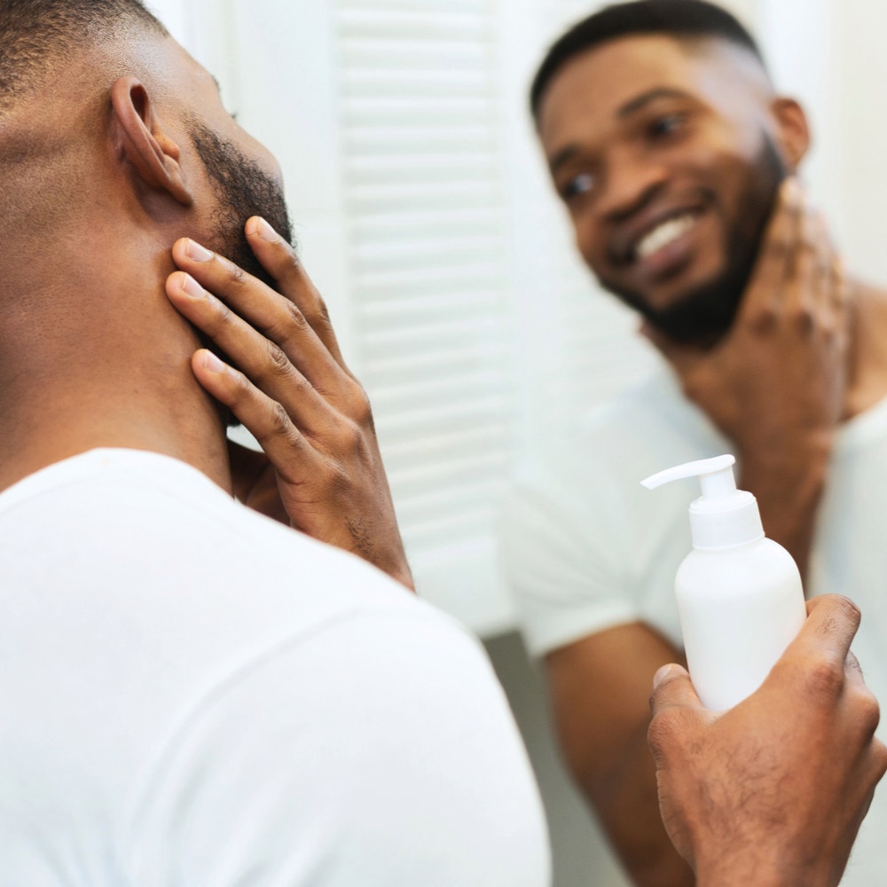 Man grooms himself in the mirror.
